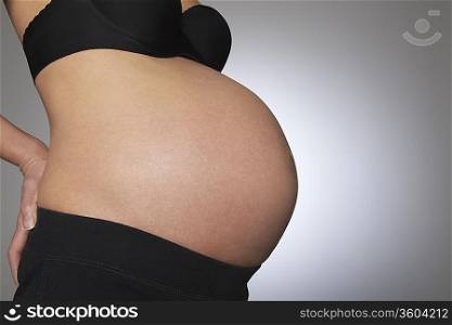 Pregnant woman, mid section, side view, studio shot