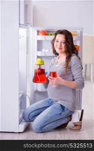 Pregnant woman near fridge looking for food and snacks