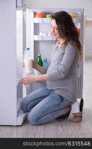 Pregnant woman near fridge looking for food and snacks