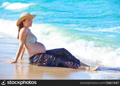 Pregnant woman on the beach playing with waves