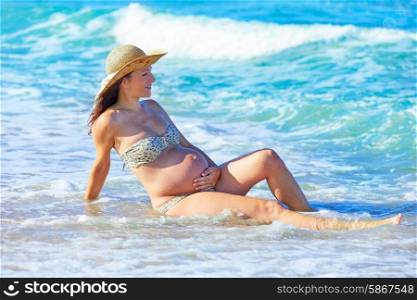 Pregnant woman on the beach playing with waves