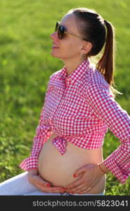 Pregnant woman outdoors at sunny summer day