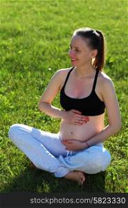 Pregnant woman outdoors at sunny summer day