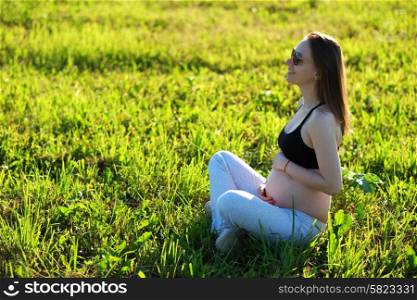 Pregnant woman outdoors at sunny summer day