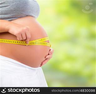 Pregnant woman outdoors, measuring abdomen, walking in the park, fresh air, healthy pregnancy, happy motherhood, love concept