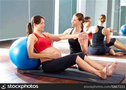 pregnant woman pilates exercise fitball at gym with personal trainer