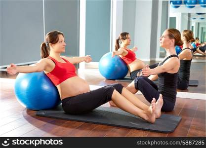 pregnant woman pilates exercise fitball at gym with personal trainer