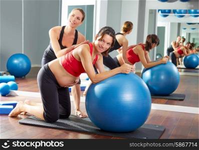 pregnant woman pilates fitball exercise workout at gym with personal trainer