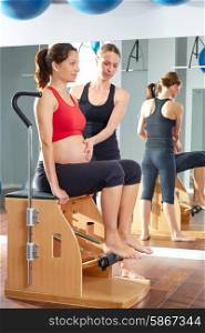 pregnant woman pilates leg pumps exercise on wunda chair with personal trainer