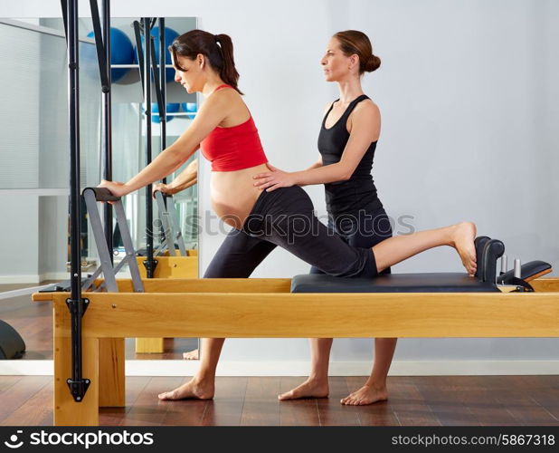 pregnant woman pilates reformer cadillac exercise workout with personal trainer