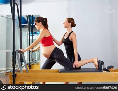 pregnant woman pilates reformer cadillac exercise workout with personal trainer