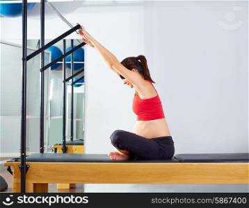 pregnant woman pilates reformer forward push through exercise workout at gym