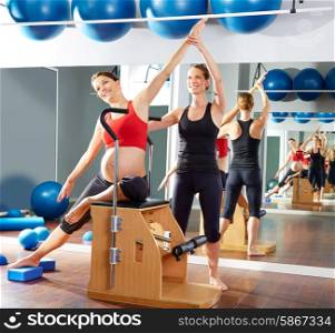 pregnant woman pilates side stretch exercise on wunda chair with personal trainer