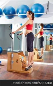 pregnant woman pilates tendon stretch exercise in wunda chair at gym indoor