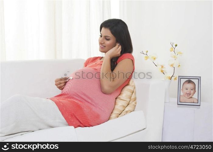 Pregnant woman putting earphones on stomach