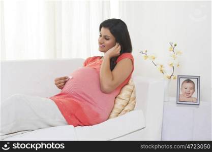 Pregnant woman putting earphones on stomach
