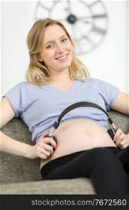 pregnant woman putting headphones to her abdomen
