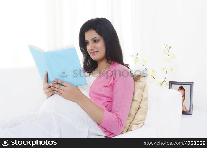 Pregnant woman reading a book on a couch