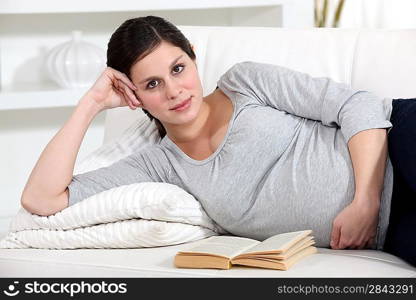 Pregnant woman reading in bed