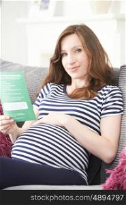 Pregnant Woman Reading Leaflet With Medical Advice