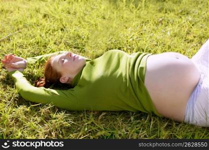 pregnant woman redhead laying on grass garden park relaxed