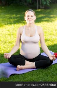 Pregnant woman relaxing and meditating at park