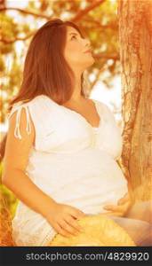 Pregnant woman relaxing in autumnal forest, looking up, spending time on fresh air, autumn season, happy pregnancy, new life concept