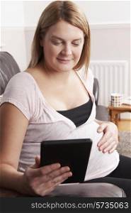 Pregnant Woman Relaxing With E Reader At Home