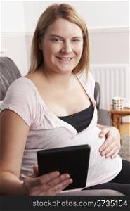 Pregnant Woman Relaxing With E Reader At Home