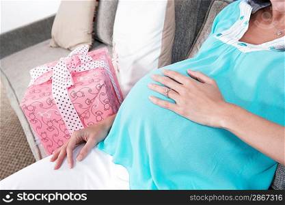 Pregnant woman resting by gift mid section