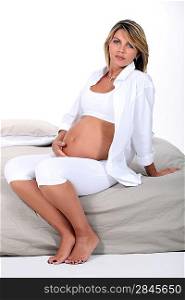 Pregnant woman sat on bed
