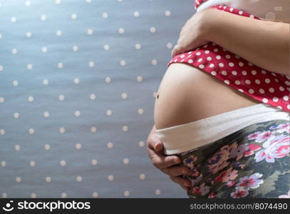 Pregnant woman shows his belly. Blue background