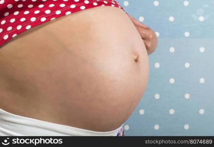 Pregnant woman shows his belly. Blue background