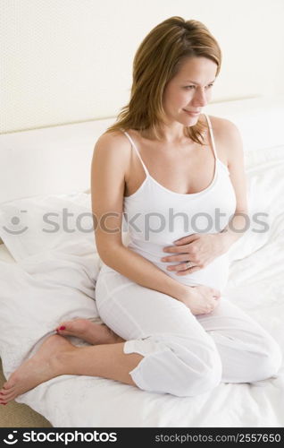 Pregnant woman sitting in bed smiling