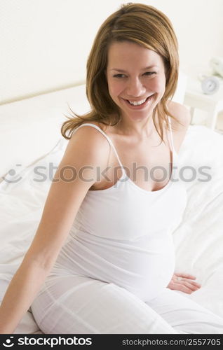 Pregnant woman sitting in bed smiling