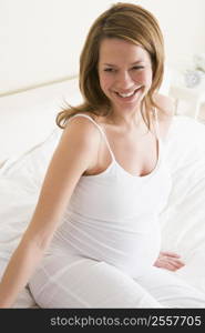 Pregnant woman sitting in bed smiling