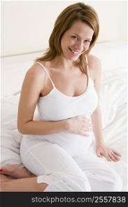 Pregnant woman sitting in bed smiling