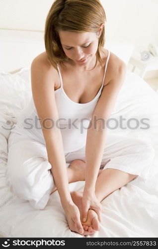 Pregnant woman sitting in bed smiling and rubbing feet