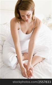 Pregnant woman sitting in bed smiling and rubbing feet