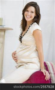 Pregnant woman sitting in living room smiling