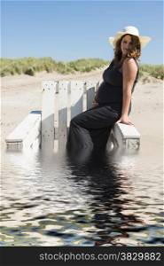 pregnant woman sitting on chair on the beach in the water