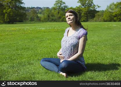 Pregnant woman sitting on grass