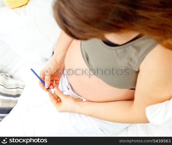Pregnant woman sitting on sofa at home and knitting for her baby. Close-up.&#xA;