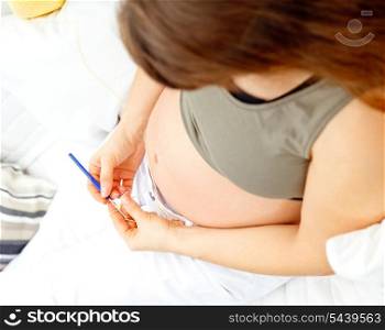 Pregnant woman sitting on sofa at home and knitting for her baby. Close-up.&#xA;