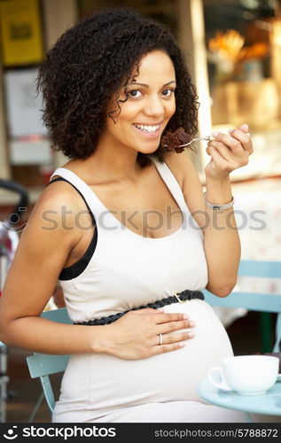 Pregnant woman sitting outside cafe