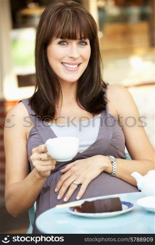 Pregnant woman sitting outside cafe