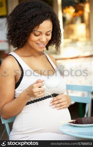 Pregnant woman sitting outside cafe