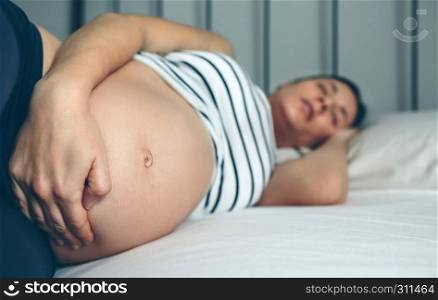 Pregnant woman sleeping and holding her belly. Pregnant woman sleeping in bed