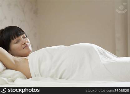 Pregnant woman sleeping on bed