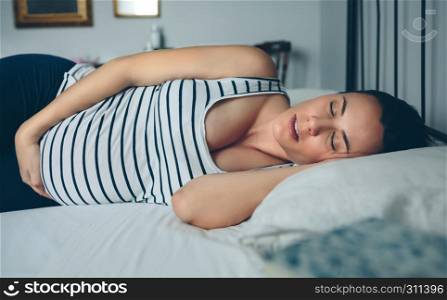 Pregnant woman sleeping on her side in bed. Pregnant woman sleeping in bed